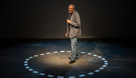 Tyrone stands in the middle of the circle of cards on the floor laughing